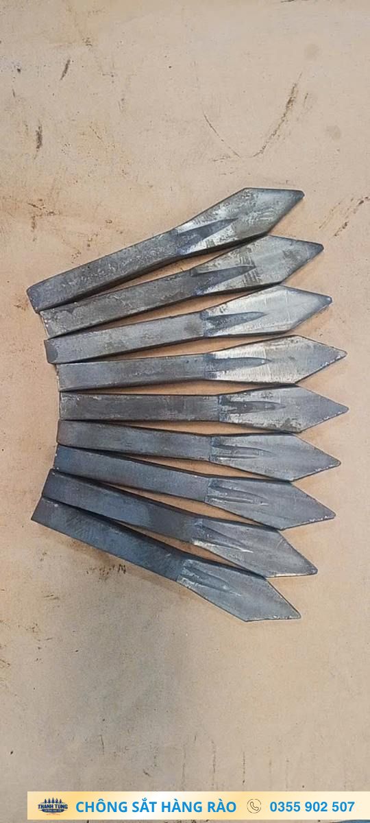 Các đầu chông sắt dạng mũi mác xếp chồng trên nền xưởng